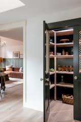 This pantry defines its own space through its dark olive green color, with metal wire grid sheeting doors, and antique doorknobs.