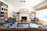 Eclectic bohemian living room ties multiple patterns and bright colors together while focused on a brick fireplace with a fresh coat of paint and custom built bookshelves.