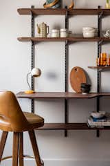 Custom built chestnut wall shelving is used as extra storage space or a writing desk for a previous unused empty wall.