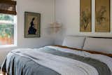 Zen inspired bedroom with natural toned bedding, antique artwork, and twin wicker pendants.