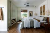 Neutral cream tones and a honey/chestnut vintage furniture set are the staples for a zen inspired bedroom. Calming antique artwork, twin wicker pendants, and a light green built-in wardrobe complete this open and airy bedroom.