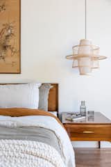 Vintage honey/chestnut headboard and bedside tables are the staples for twin wicker pendants, zen art work, and neutral bedding.