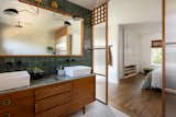 Antique dresser turned tiled bathroom vanity has custom screen walls built to provide privacy between the multi green tiled shower and neutral colored and zen ensuite bedroom.