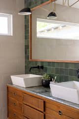 Transformed refurbished dresser turned bathroom vanity. Twin sinks, black hardware, gold/black sconces and multi toned green tile are the backdrop for this signature piece.