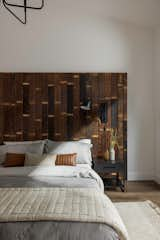 Ensuite bedroom with custom built reclaimed wood headboard, black matte side tables and sconces, a natural woven rug, and plush cream and grey Parachute bedding with a leather lumbar pillow.