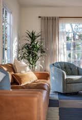 A modern sleek caramel leather couch, paired with a funky vintage baby blue swivel chair creates a warm and inviting living room.