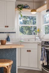 Blue penny tile and subway tile paired with a yellow pendant pops against classic white kitchen cabinetry with a quartz corner sink.