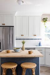 A butcher block free standing kitchen island with blue penny tile creates stylish functionality for this natural and airy feeling kitchen.