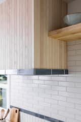 Stained white oak paneling and blue subway tile complete this custom wrapped kitchen range hood and backsplash.