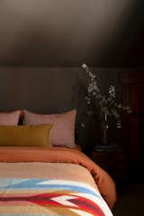 A moody grey neutral wall allows the guest bedrooms fabrics a place to shine through bright sheets from Parachute, throws from Pendleton, and accent various pillows.
