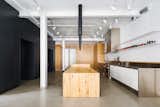Minimalist loft in Old Montreal. Kitchen island made out of reclaimed wood with custom lights. The cabinetry that divides the spaces is in white oak.