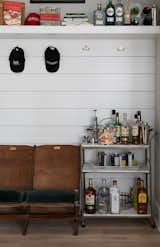 Living Room A bar stand in the shiplap-laced cove and coat rack by the pantry is always ready for Stephen’s storied Pinewood Forest gatherings.  Photo 7 of 8 in Pinewood Forest Huxley Terrace Home by Emily