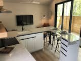 Kitchen, Range, Range Hood, Light Hardwood Floor, and White Cabinet Storage abounds in the kitchen with space to eat at the bar. The sliding doors open completely onto the private deck.  Photo 3 of 8 in Minimalism and Luxury Meet In Pinewood Forest Micro Home by Emily