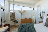 Primary Suite with 3ft by 12ft trapezoid clerestory window and plenty of natural light and a cozy nook with a Serena & Lily hanging rattan chair.