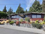 The landscape surrounding the home includes native plantings and extensive gardens, and a forested setting.