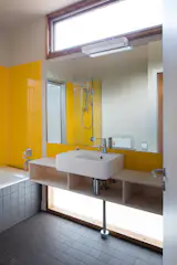 Brightly coloured panels of perspex add sense of joy to holiday house , while windows above and below vanity flood the room with light. Simple joinery of low formaldehyde plywood provide relaxed quality and plenty of space for guest use. 