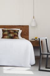 V-grooved timbers lining boards add texture and warmth to bedroom with solid timber bedhead and side table accents of warmth frame the white of the bedding. 