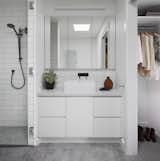 Simple bathroom and robes with white cupboards and tiling allow light to permeate through the internalised space 