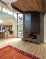 Living Room, Ceiling Lighting, Pendant Lighting, Medium Hardwood Floor, Gas Burning Fireplace, and Recessed Lighting The new steel chimney wrap radiates heat from the new gas-powered fireplace into the living room.  Photo 1 of 7 in Bellevue Home Remodel by WC STUDIO