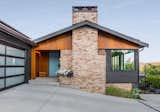 Low-maintenance black corrugated metal and wood veneer panels complement the salvaged existing brick.