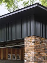 Detail of corner with brick, metal panels, and roof eave