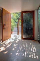 The entrance to Lua, Moon House, features large hardwood doors with aluminium panelling that are patterned with cut-out motifs of the lunar cycle. 

The design catches the afternoon light at an obtuse angle, casting a carpet of shadowplay across the home's concrete floor foyer.  