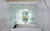 White marble clads the walls and floor of the master bathroom