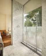 The guest bathroom is clad in white marble and stainless steel hardware
