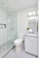 Walk in shower with concrete tile flooring and concrete countertops.