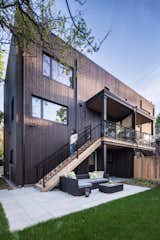 Rear exterior of this contemporary residence.  Features entry from lower and middle floors, grassy back yard and patio spaces for entertaining.  