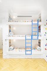 The playroom is sound-proofed and features a rainbow of color. "We built the bunks the height of the apartment allowed and customized them to maximize the fun," she says. "Behind the beds there's this wallpaper, I See You by Cavern Home—it's a wallpaper you can create faces on, so the kids are encouraged to draw on the walls." The bedding textile is from Studio Four NYC.