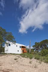 The home is composed of four materials: white standing-seam metal, Lueders limestone, wood, and white plaster, the latter used for exterior walls where the pitched volumes have been cut away.