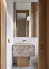 The powder bathroom features a custom stone sink and white oak vanity base built by the homeowner.
