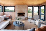 The screened porch features white-washed cedar walls and a clear cedar ceiling. Wrought Studio chairs and a Ratana sectional surround a coffee table from Article.