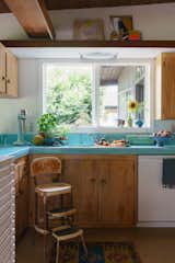 Sunflowers from her front yard and fresh produce add more color to the original turquoise kitchen, which includes an antique chair and breakfast table, mementos from her first apartment in New York.