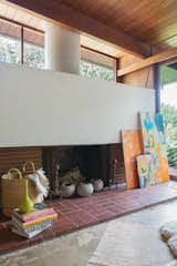 The home's original fireplace has been painted white, juxtaposing the living room's many art pieces.