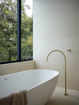 In the bathroom, a poured concrete sink makes everything feel built-in. "The tub’s curve mimics the architecture,
