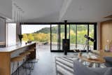 Dining Room, Chair, Table, Stools, Floor Lighting, Wall Lighting, Table Lighting, Wood Burning Fireplace, Concrete Floor, and Ceiling Lighting The COSMOS house is a frame to nature outside.  Photo 6 of 15 in COSMOS house  that lifts your spirit by Yaryna Bakhovska