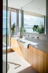 The bathroom has a custom white oak vanity, tile floors, and a casement window.&nbsp;