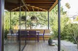 A cedar deck, built-in bench, and Fermob Costa table and chairs under a new porch roof serve as a year-round dining area. 