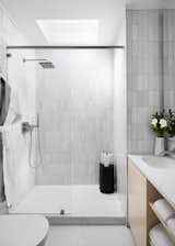 All the bathroom surfaces are tiled, and the vanity is designed in the Scandinavian modern manner.