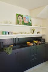 A kitchenette in the ADU is matte black with shelves matching the walls to recess into the background.