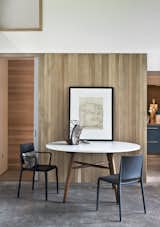 The white oak millwork finishes throughout the rooms are repurposed from ceiling slats to offer a warm counterpoint to the concrete slab floor. The dining table is by Hudson Workshop, and the matte black chairs are by Allermuir.