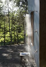 The secluded location of the house at the edge of a retired shale bank allows the luxury of an open outdoor shower. Corrugated steel siding provides a durable, zero-maintenance exterior finish and captures the changing sun and woodland shadows.