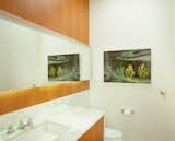 The new bathroom with a horizontal ribbon of mirror, underlit. A marble wainscot unifies that wall and its elements.