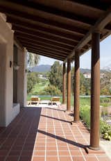 This view from the entry vestibule. A paved floor of custom terracotta tiles, covered by a deep covered wood pergola, leads to a view of the pool in the foreground, the Riviera Country Club in the middle ground, and the Santa Monica Mountains in the background.

The idea of a passively shaded, cooled building, along with radiant heat in all floor surfaces, inside and out, made air-conditioning not necessary. Our client wanted to feel that he was living life simply as they would have when the original house was built, without the need for modern  cooling and heating technologies.