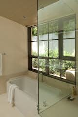 A large steel sash window is placed next to the tub. An awning window right next to the  head of the tub opens so that the bather feels they are in the garden. A small fountain has been placed just outside to create a tranquil environment. The bathtub is a ‘Happy D’ from Duravit, and emerges from the custom limestone tub deck.