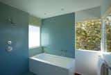 Two colors of glass mosaic tiles (Trend, from Ann Sacks) are used to distinguish two intersecting wall planes. Windows on the street side are translucent, both for privacy and to casts a soft light against the tile. The bathtub is encased in white Caesarstone.