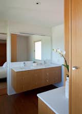 All cabinets are white oak. The vanity appears to float. Drawers (customized to fit around the sink drains) instead of cabinet doors emphasize the horizontality. A large pencil-polished edge mirror floats off the wall, and the light is a long LED fixture at perfect daylight temperature.