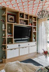 A custom built in media cabinet by Good Dog Rosie offers a sleek solution for housing entertainment equipment and showcasing keepsakes from the couples travels.